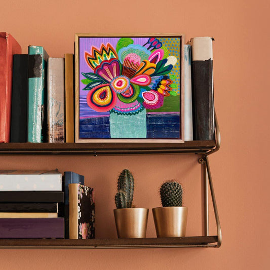 Colorful floral artwork on a shelf with books and small plants against a brown background