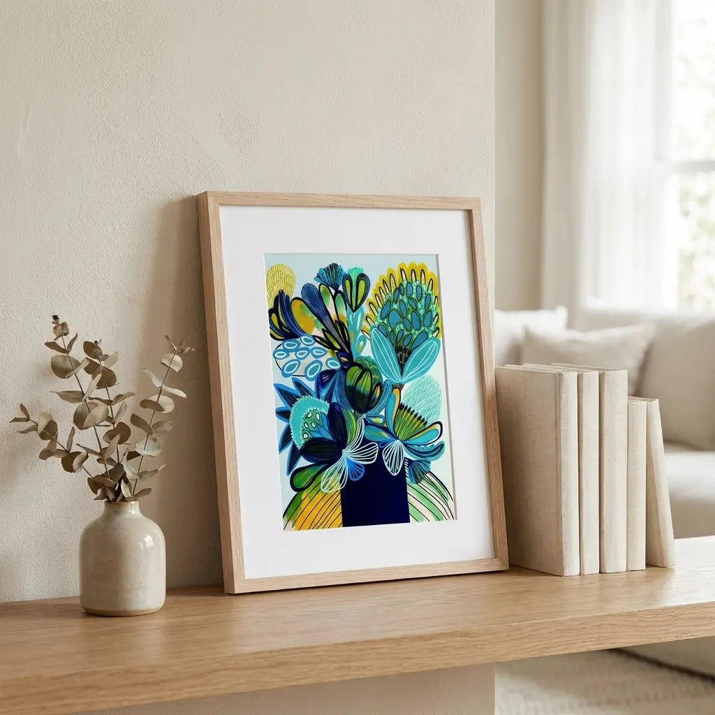 Framed mpdern abstract artwork on a wooden shelf with a vase and books.