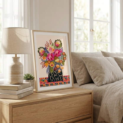 Framed colorful floral artwork on a wooden dresser next to a bed with pillows.