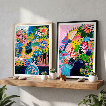 Colours of Summer abstract wall art print set by Kirsten Katz: two framed modern abstract floral prints in bold pink, yellow, blue and green, displayed on a timber shelf with small succulents