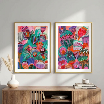 Kimberley wall art print set by Kirsten Katz: two framed modern botanical prints of stylised outback wildflowers in pink, teal and purple on warm coral grounds, hung above a timber sideboard