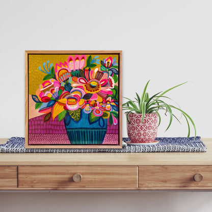 Colorful floral artwork on a wooden surface with a plant