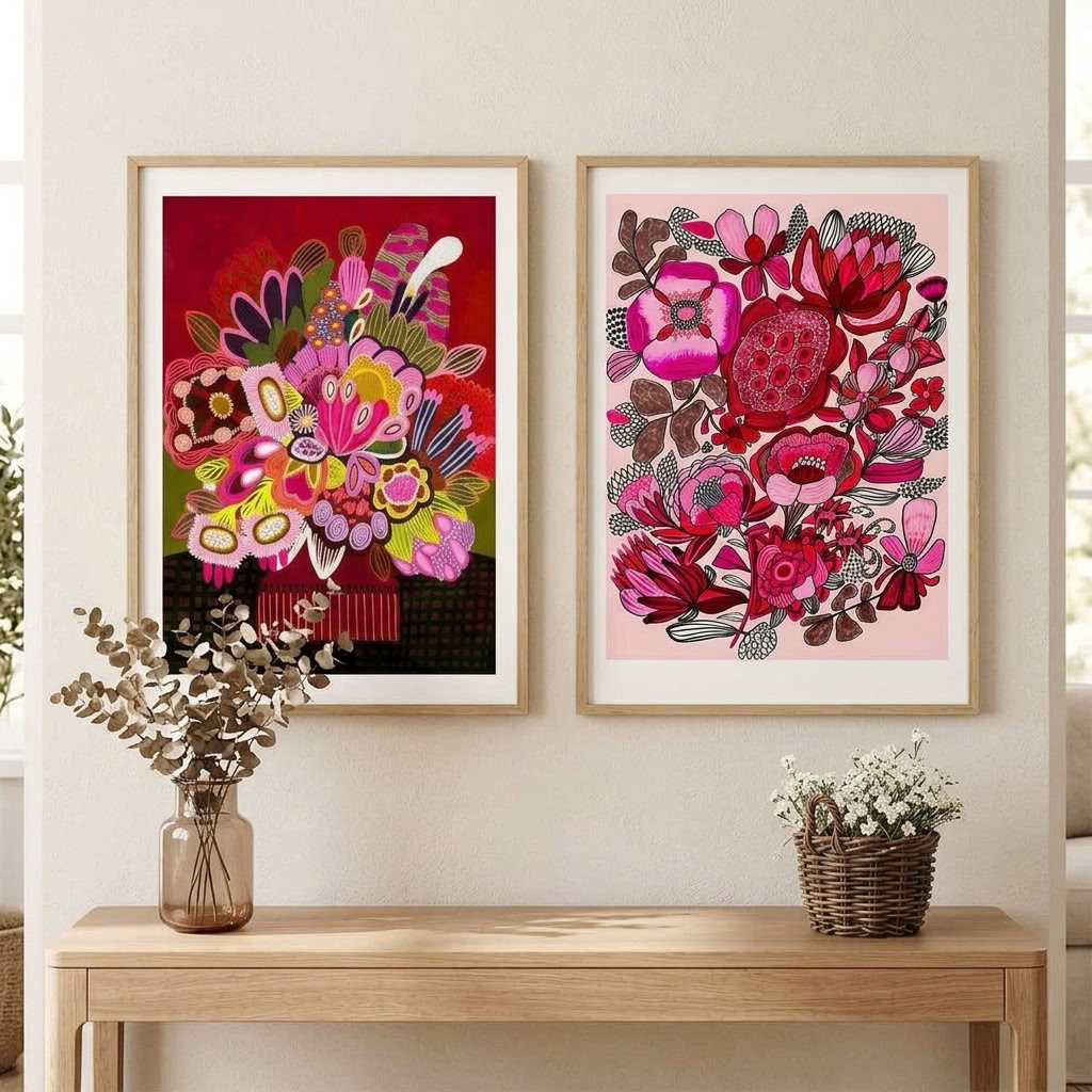 Rosa Blooms wall art print set by Kirsten Katz: two framed modern botanical prints, a floral still life on deep red and a pink and crimson floral on soft blush, hung above a timber console table
