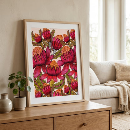 Australian botanical wall art print with red waratahs styled in a contemporary living room on a wooden side table with a couch and plant in the background