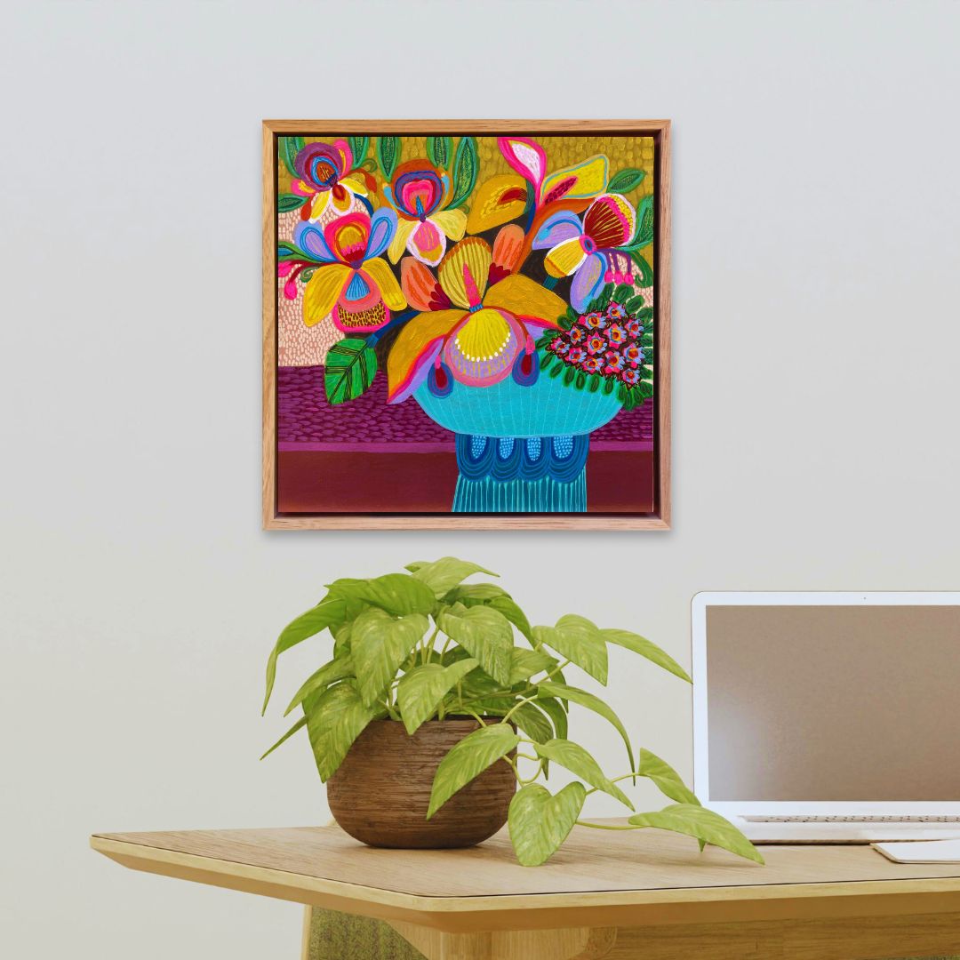 Colorful abstract painting on a wall above a desk with a plant and laptop.