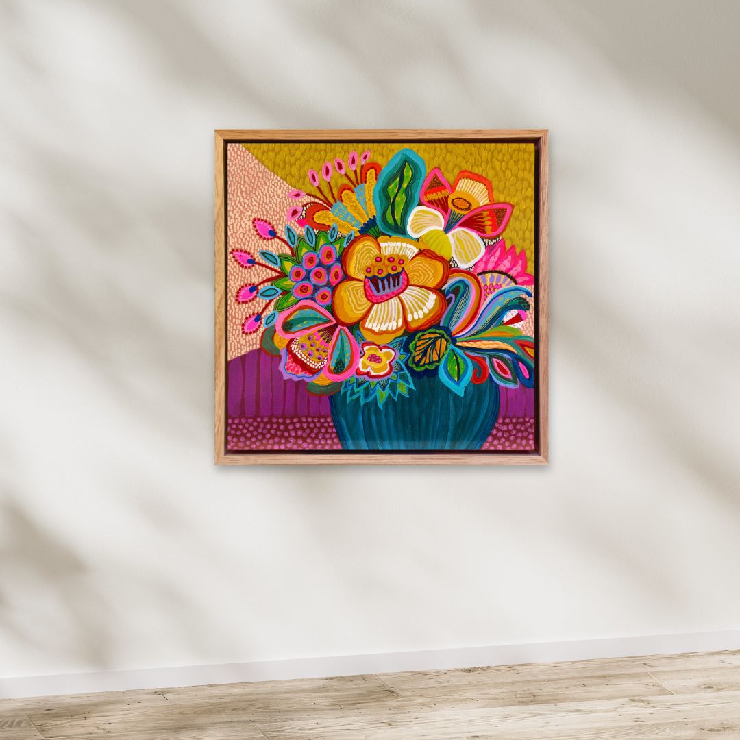 Colorful floral artwork in a wooden frame on a white wall.