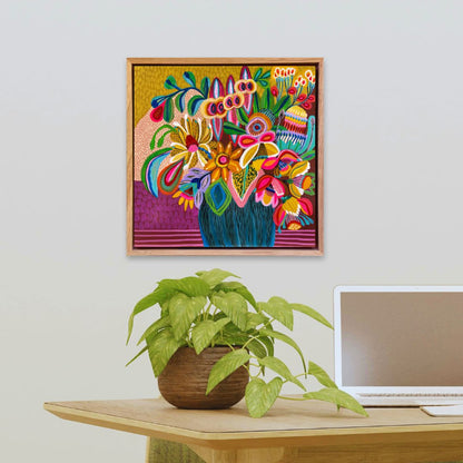 Colorful floral artwork on a wall above a desk with a plant and laptop.
