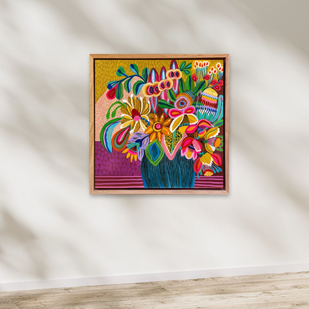 Colorful floral artwork in a wooden frame on a white wall.