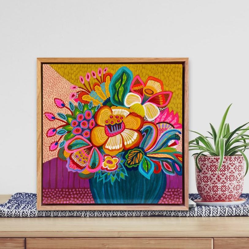 Colorful floral artwork on a wooden shelf with a plant