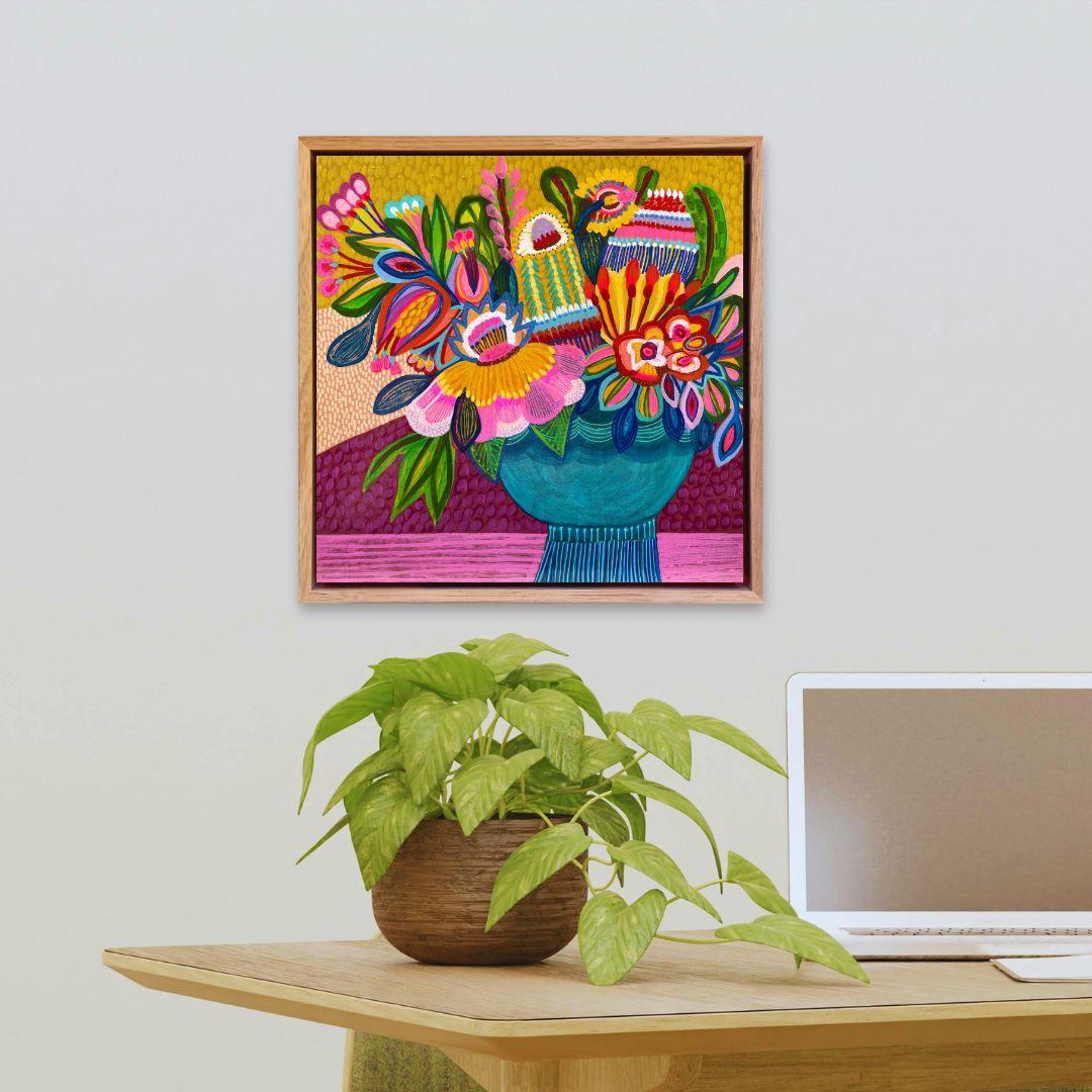 Colorful abstract artwork on a wall above a desk with a plant and laptop.