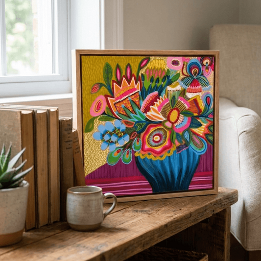 Colorful floral artwork on a wooden table with a cup and books in a cozy living room.